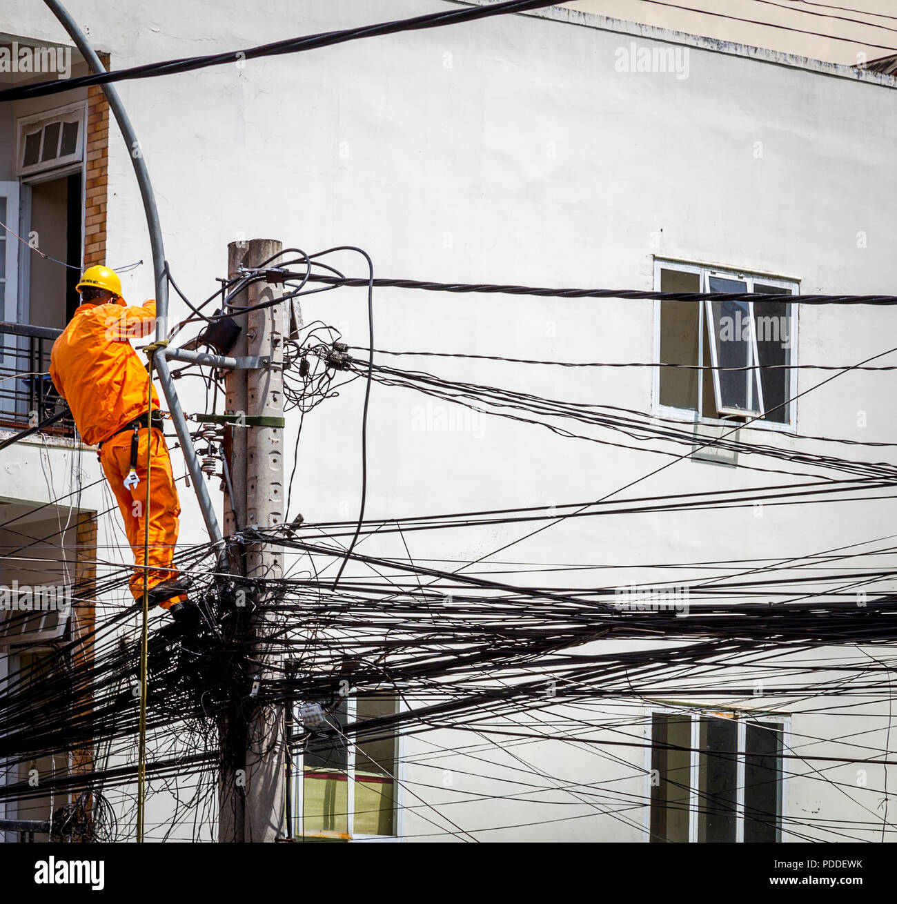 Repair man balances on cables in Vietnam high in the air Stock Photo