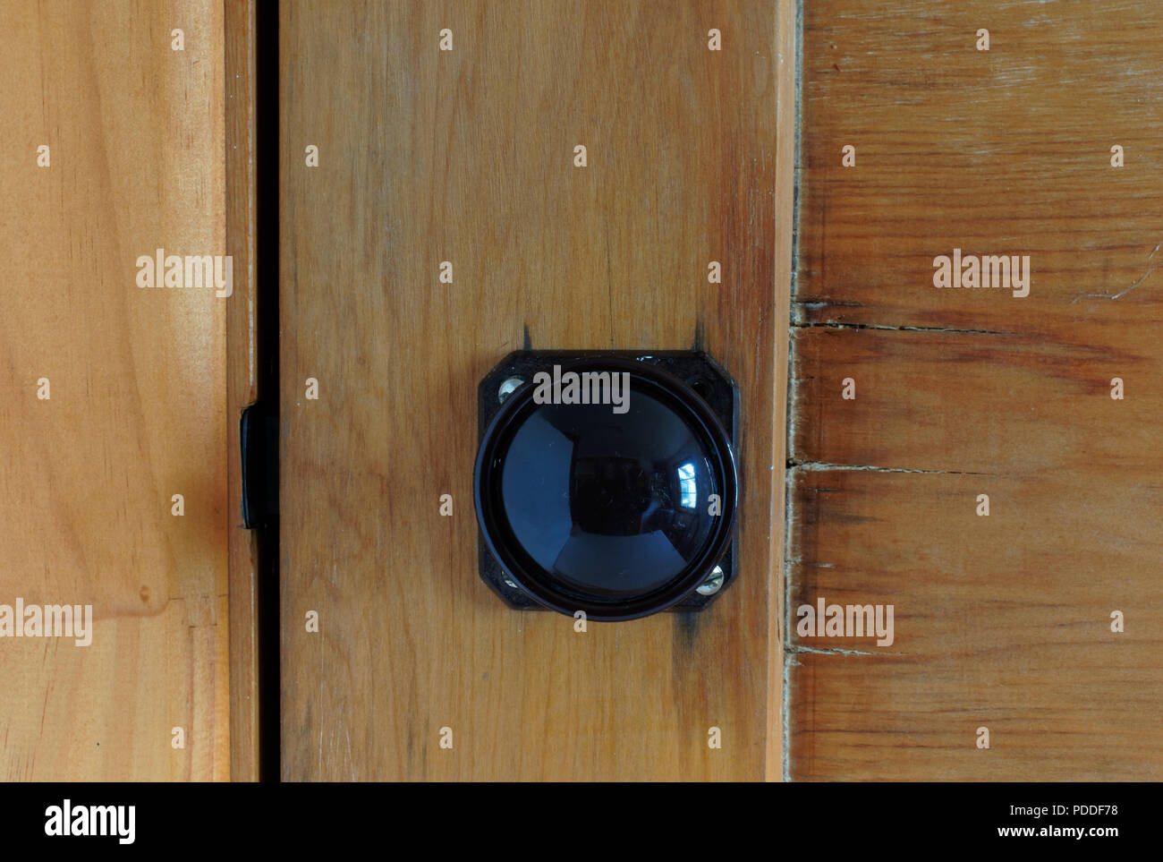 Black shiny Bakelite door handle on a wooden door, with a screw missing Stock Photo