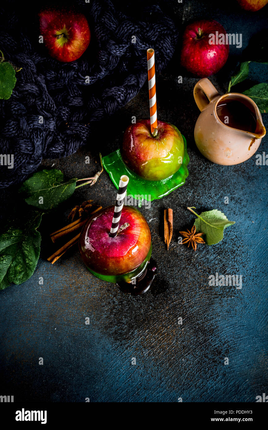 Traditional autumn delicacy, apples in caramel glaze. On a dark background, with apples, leaves, caramel sauce and a warm blanket. Copy space for text Stock Photo