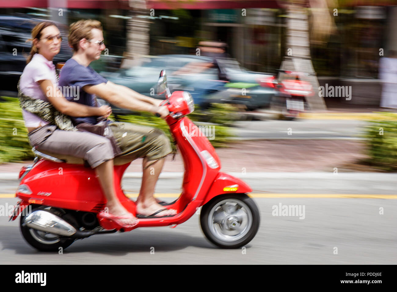 Miami Beach Florida,Washington Avenue,man men male,woman female women,red,motor scooter,alternative transportation,without helmet,unsafe,couple,two 2 Stock Photo