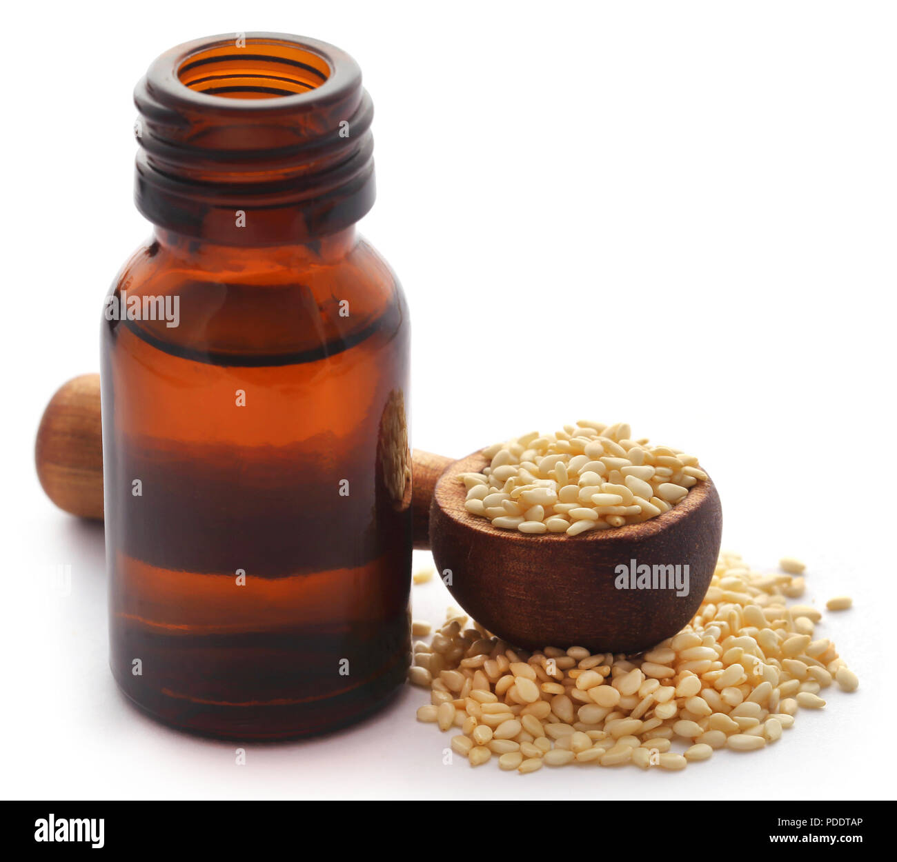 Peeled sesame seeds with oil in a amber bottle Stock Photo