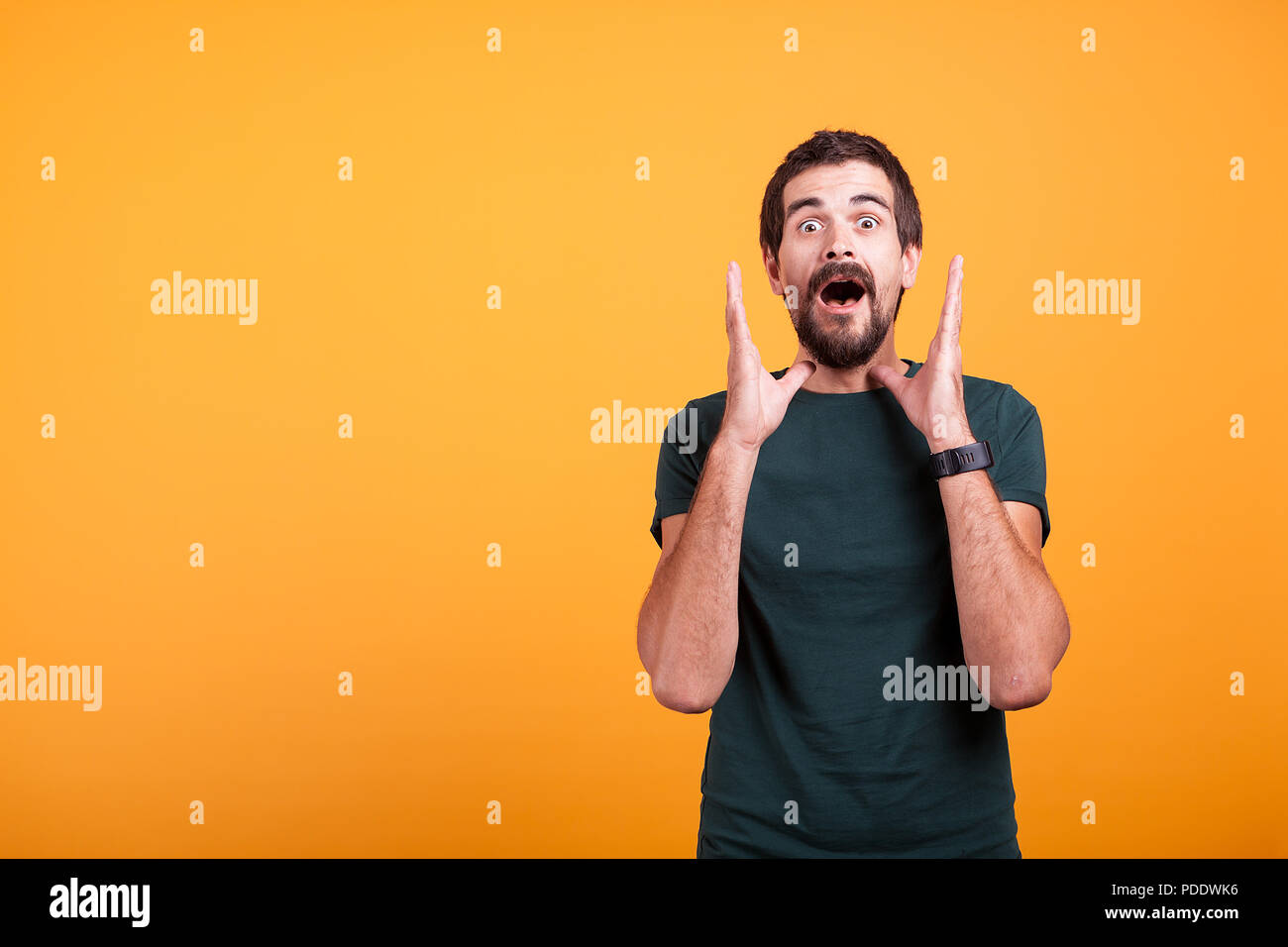 Shocked man with hands at his face looking at the camera. Copyspace available for your advertisement or promo Stock Photo