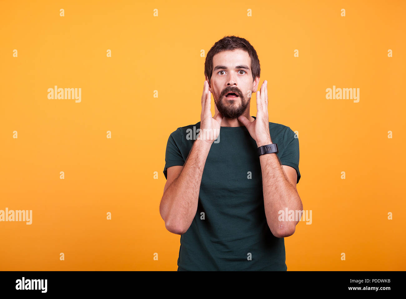 Shocked man with hands at his face looking at the camera. Copyspace available for your advertisement or promo Stock Photo