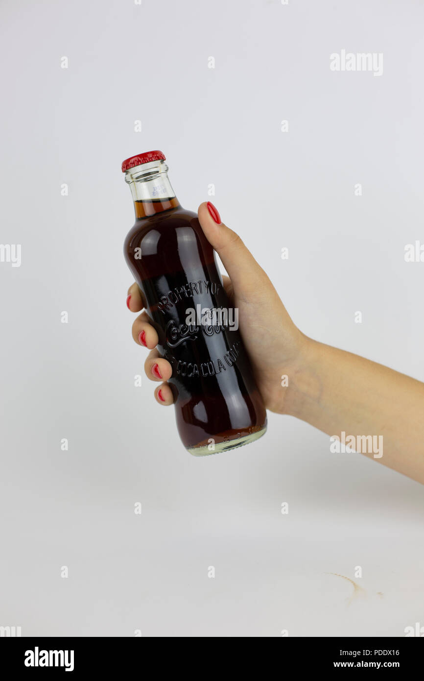 Atlanta, Georgia, USA - July 22, 2018: woman hand with red nails holding vintage historical glass coca-cola contour classic bottle from USA on white background Stock Photo