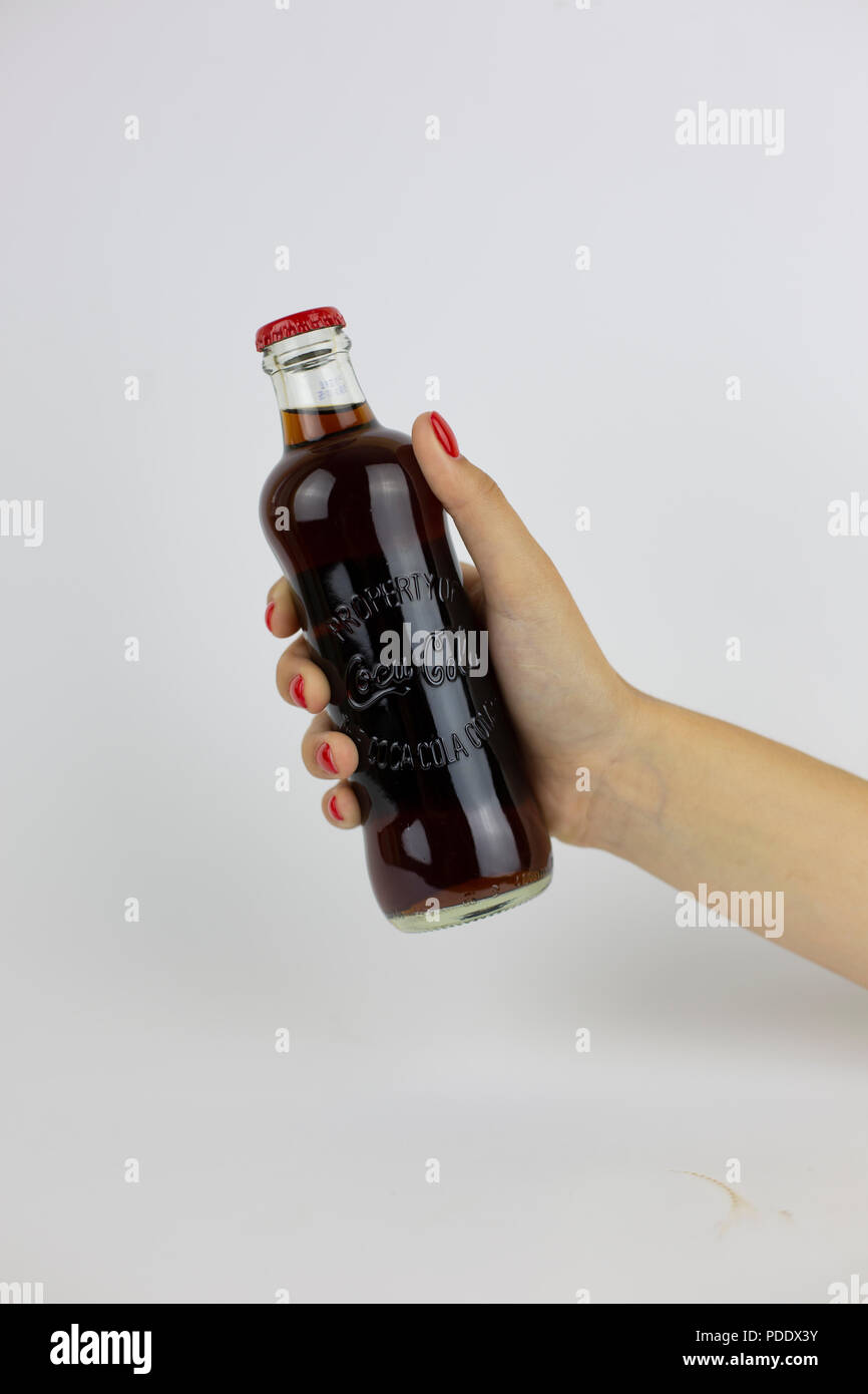Atlanta, Georgia, USA - July 22, 2018: woman hand with red nails holding historical glass coca-cola contour classic bottle from USA on white background Stock Photo