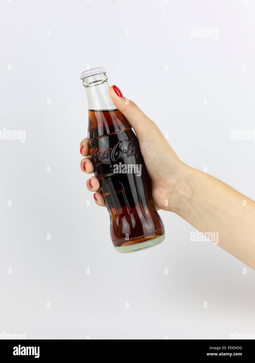 Atlanta, Georgia, USA - July 22, 2018: woman hand with red nails holding glass coca-cola contour classic bottle from France on white background Stock Photo