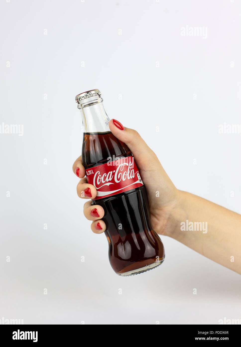 Atlanta, Georgia, USA - July 22, 2018: woman hand with red nails holding glass coca-cola contour classic bottle from Italy on white background Stock Photo