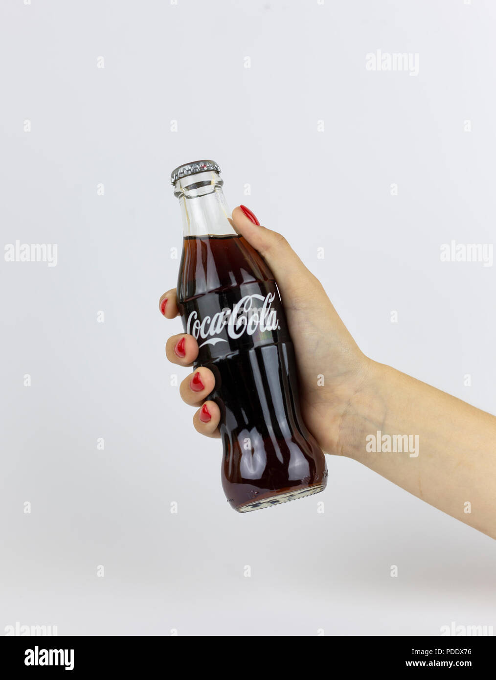 Atlanta, Georgia, USA - July 22, 2018: woman hand with red nails holding glass coca-cola contour classic bottle from with white painted logo from USA on white background Stock Photo
