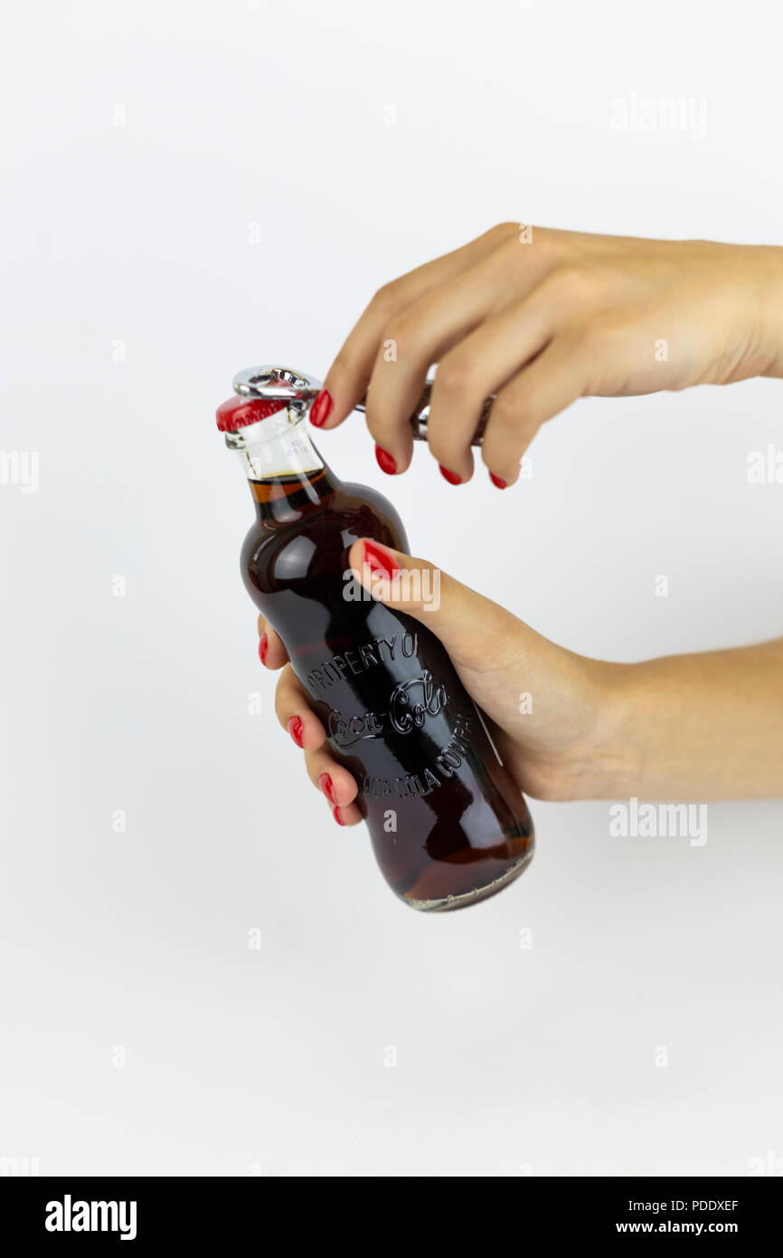 Atlanta, Georgia, USA - July 22, 2018: woman hand with red nails holding vintage historical glass coca-cola contour classic bottle from USA on white background and openingit Stock Photo