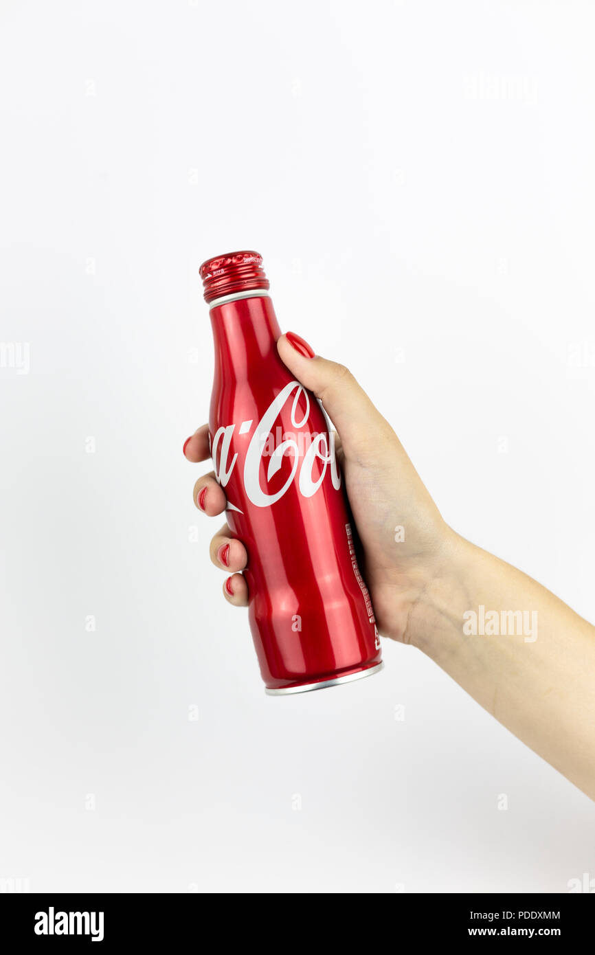 Atlanta, Georgia, USA - July 22, 2018: woman hand with red nails holding aluminum coca-cola contour classic bottle from with white painted logo from USA on white background Stock Photo