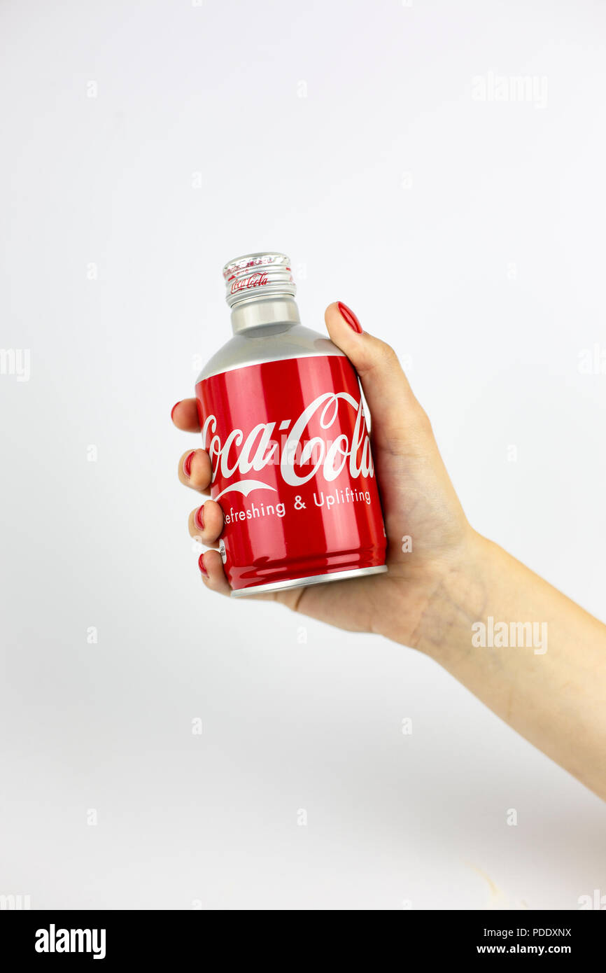 Atlanta, Georgia, USA - July 22, 2018: woman hand with red nails holding aluminum coca-cola contour bottle from with white painted logo from Japan on white background Stock Photo