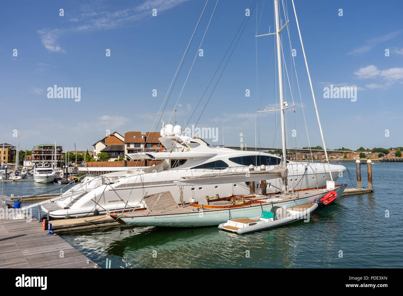 Luxury yacht and small sailboat / sailing boat moored at Ocean Village yacht harbour and marina, Southampton, Hampshire, England, UK Stock Photo