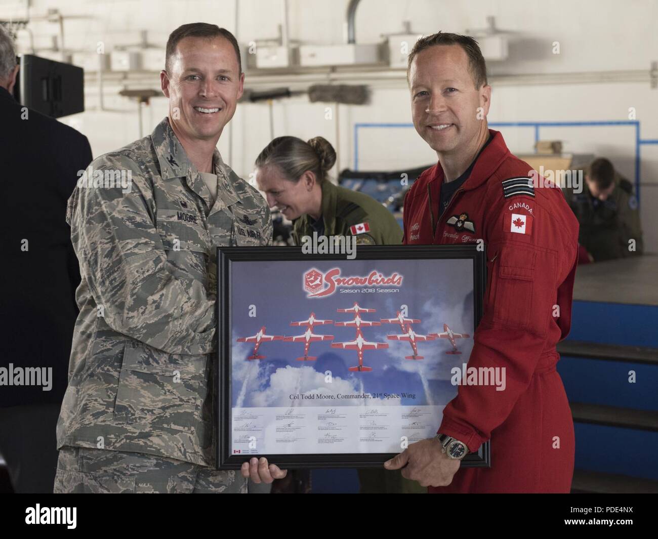 Lt. Col. Mike French (right), commander of the Royal Canadian Air Force’s Snowbirds, presents Col. Todd Moore(left), 21st Space Wing commander, with a lithograph at the North American Aerospace Defense Command's 60th Anniversary Ceremony on Peterson Air Force Base Colorado, May 12, 2018. The ceremony and static display of various NORAD aircraft was the culmination of a three-day event, which included a media tour of Cheyenne Mountain Air Force Station, the dedication of a cairn outside the commands' headquarters building memorializing the Canadians who have passed away while serving NORAD, and Stock Photo