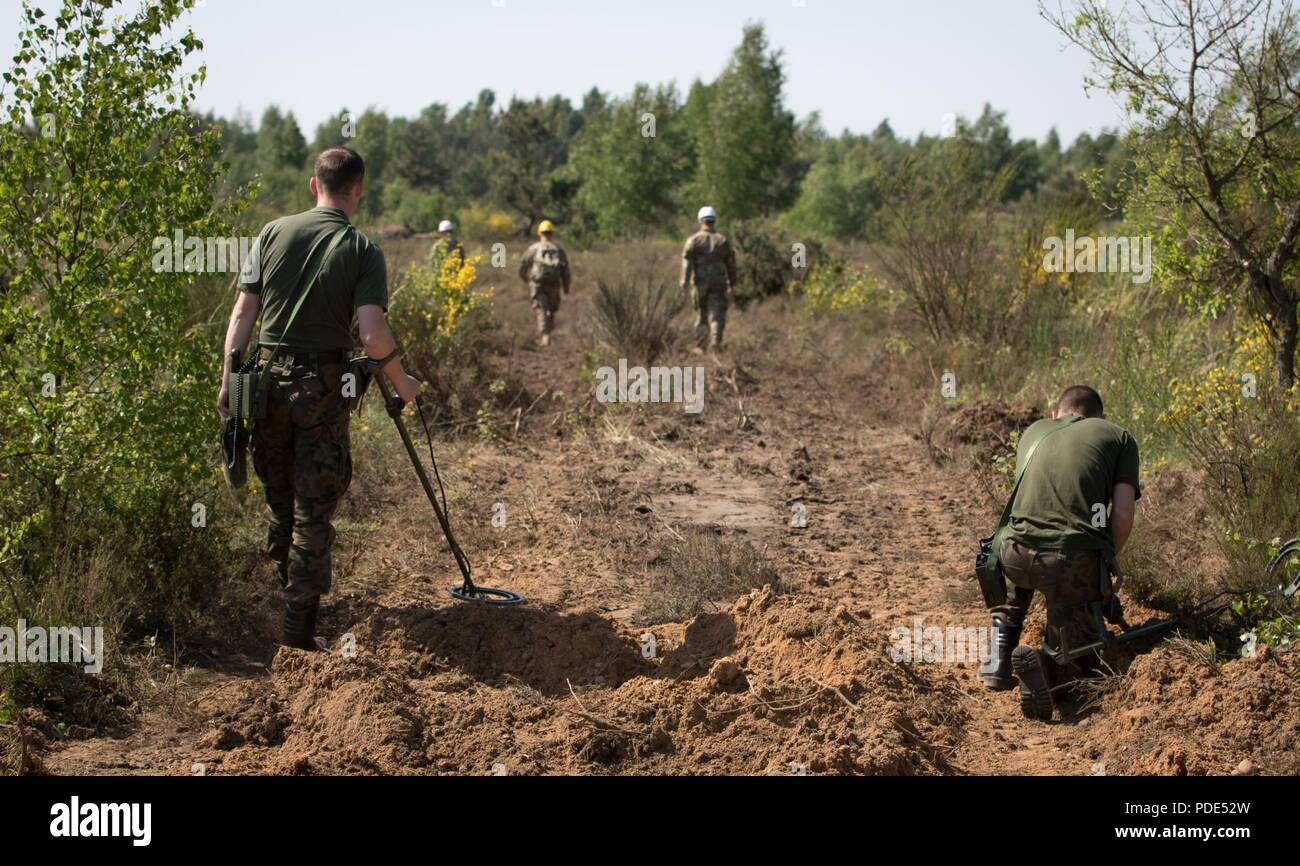 U.S. Army Soldiers responsible for construction operations visit a work site where Polish engineer soldiers are sweeping for unexploded ordnance during Resolute Castle 2018, at the Drawsko Pomorskie Training Area, Poland, May 14, 2018. Resolute Castle is a multinational training exercise for NATO and U.S. Army engineers, which supports Atlantic Resolve by promoting interoperability. Atlantic Resolve is a demonstration of the United States’ commitment to the collective security of Europe through the deployment of rotational U.S. forces in cooperation with NATO ally and partner nations. Stock Photo
