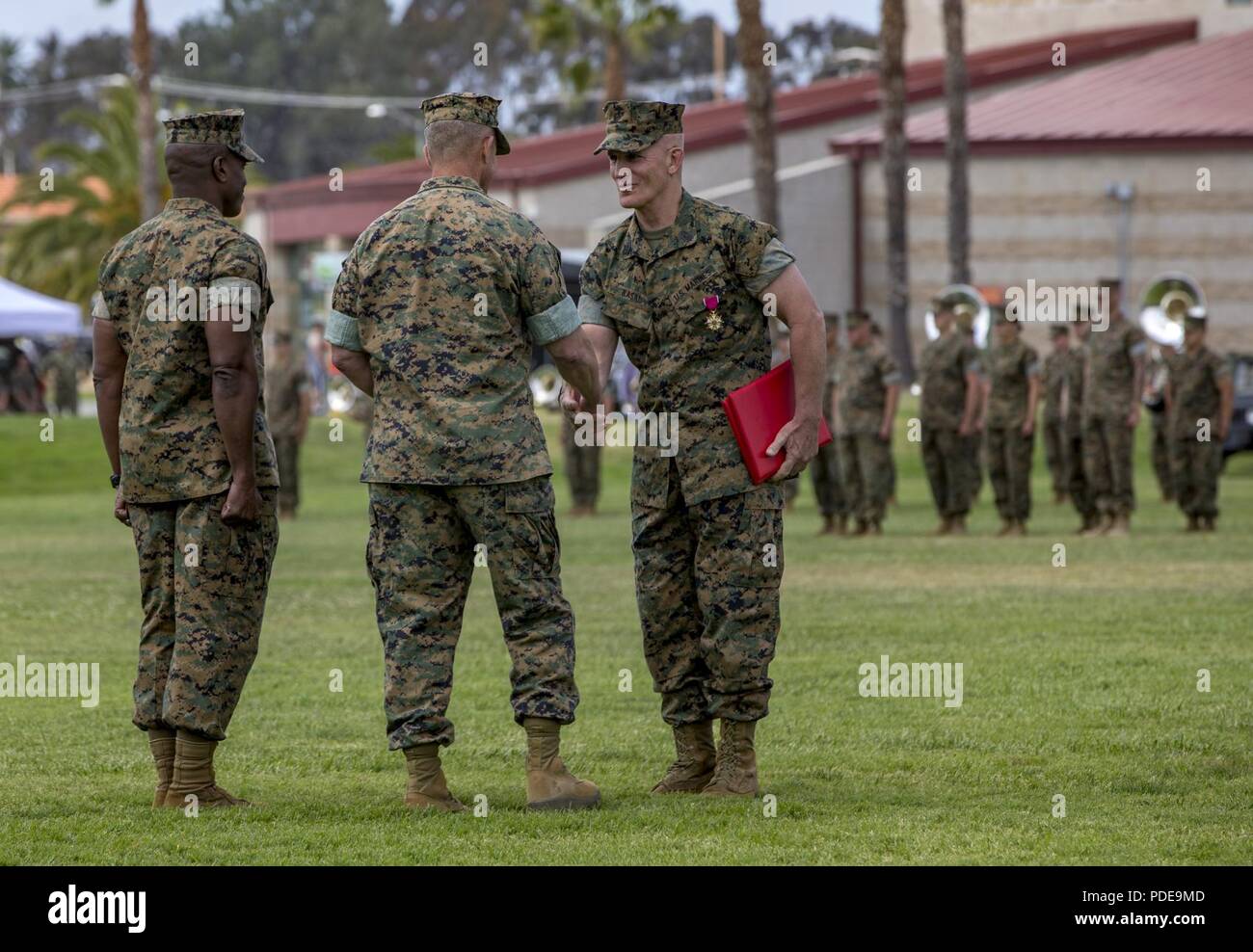 Lt. Gen. Lewis Craparotta, center, the I Marine Expeditionary Force commanding general, congratulates Sgt. Maj. Bradley Kasal, the outgoing I MEF sergeant major, on his award during a relief and appointment ceremony on Camp Pendleton, Calif., May 18, 2018. Sgt. Maj. James Porterfield replaced Kasal as I MEF sergeant major. Kasal has served as I MEF sergeant major since 2015 and is retiring from the Marine Corps after 34 years of service. Stock Photo