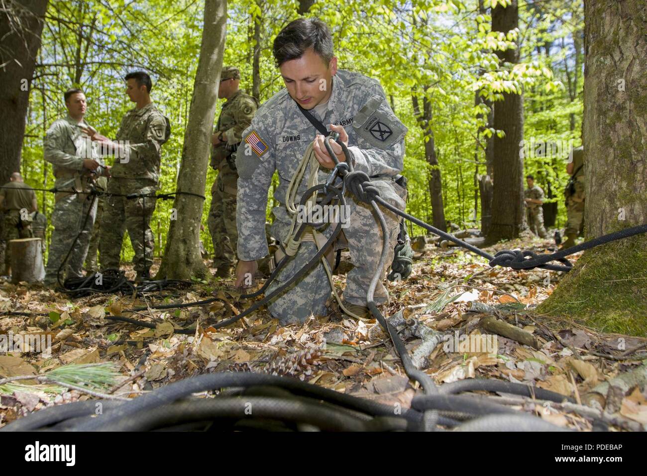 U.S. Army Spc. Jake Downs, Charlie Company, 3rd Battalion, 172nd Infantry Regiment, 86th Infantry Brigade Combat Team (Mountain), New Hampshire National Guard, sets up a medical evacuation rope system at Camp Ethan Allen Training Site, Jericho, Vt., May 18, 2018. As part of the basic military mountaineer course at the Army Mountain Warfare School students learn how to utilize the knots and systems they’ve learned to evacuate casualties on a SKEDCO litter. Stock Photo
