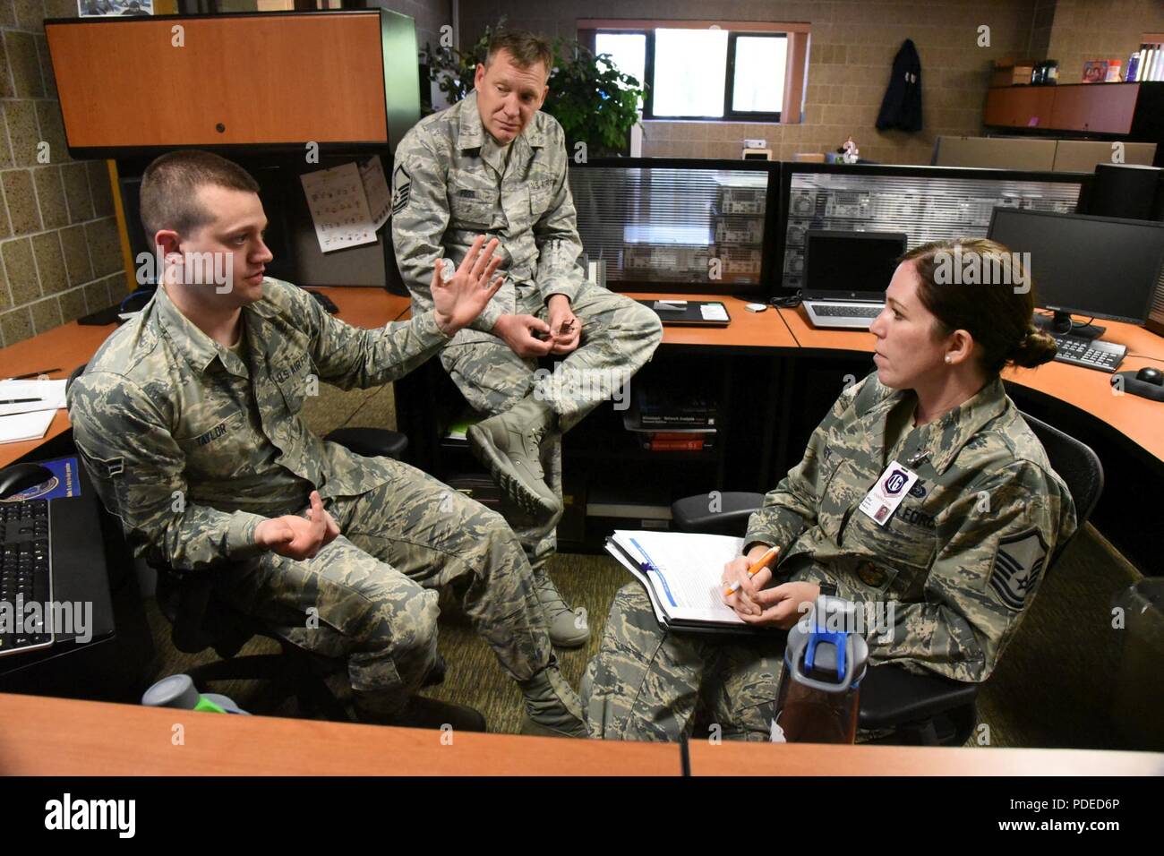 U.S. Ai rForce Master Sgt. Daimie Mabrey, of the Air Combat Command (ACC)  inspector general team, right, discusses unit standards and practices with  Airman 1st Class Brock Taylor, left, and Master Sgt.
