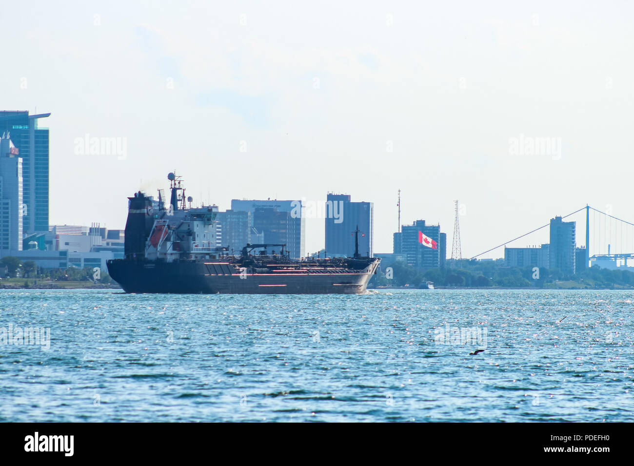 Barge floating down Detroit River viewing from Belle Isle. Windsor, Canada in view. Stock Photo