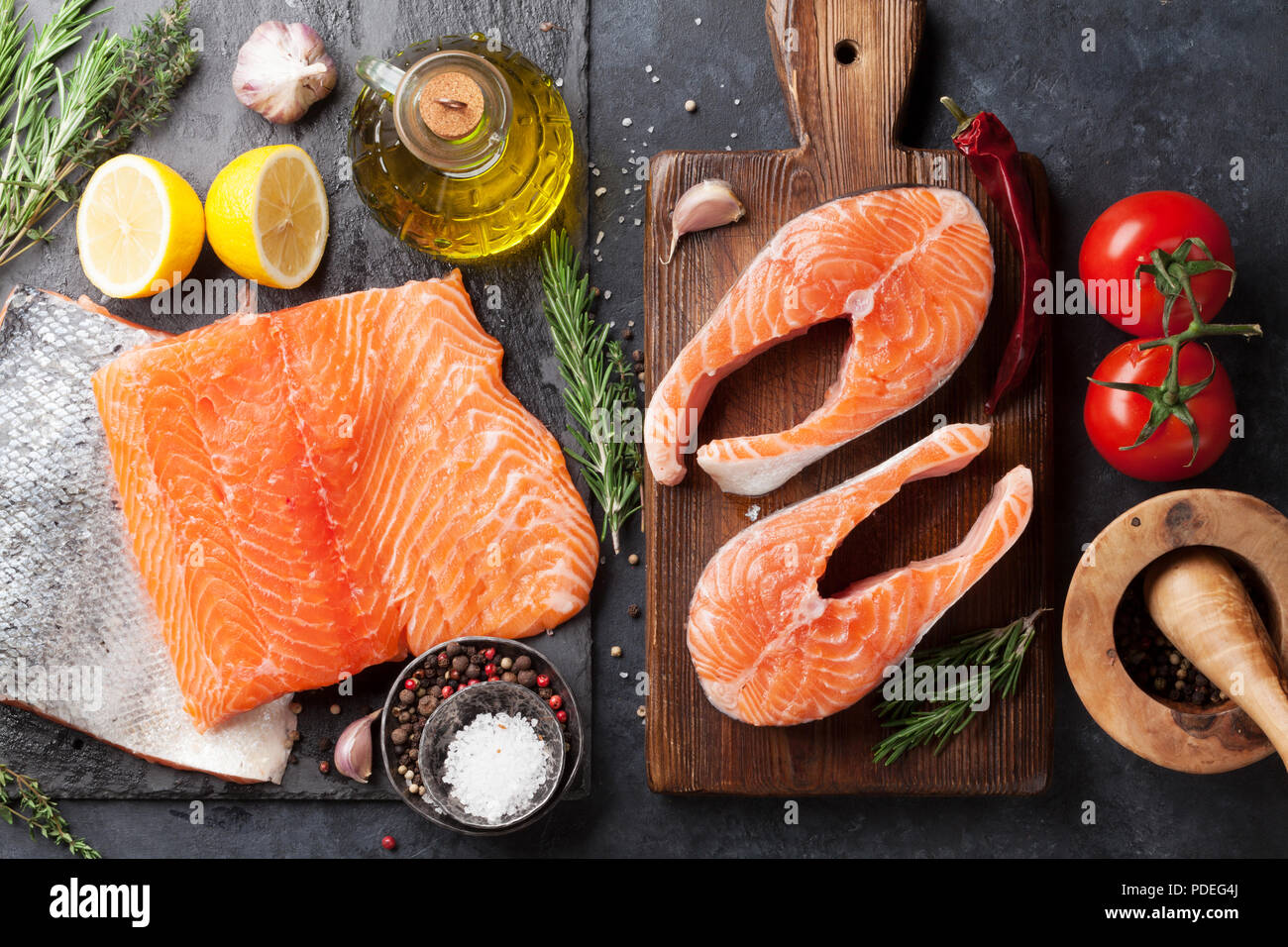 Raw salmon fish steaks and fillet with spices cooking on cutting board ...