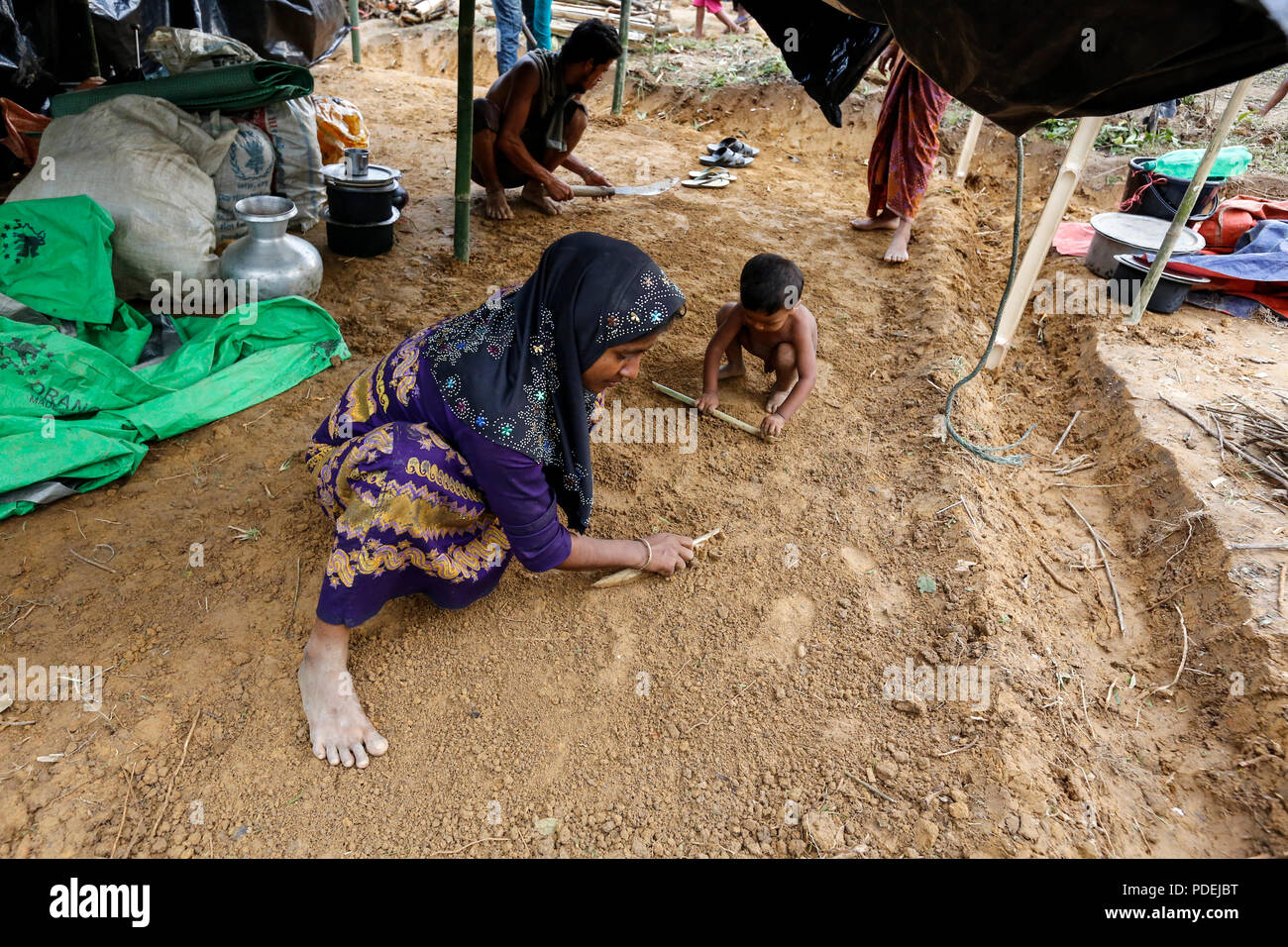 A Rohingya woman builds her new shelter on a hill at  Palongkhali in Ukhia. Cox's Bazar, Bangladesh Stock Photo