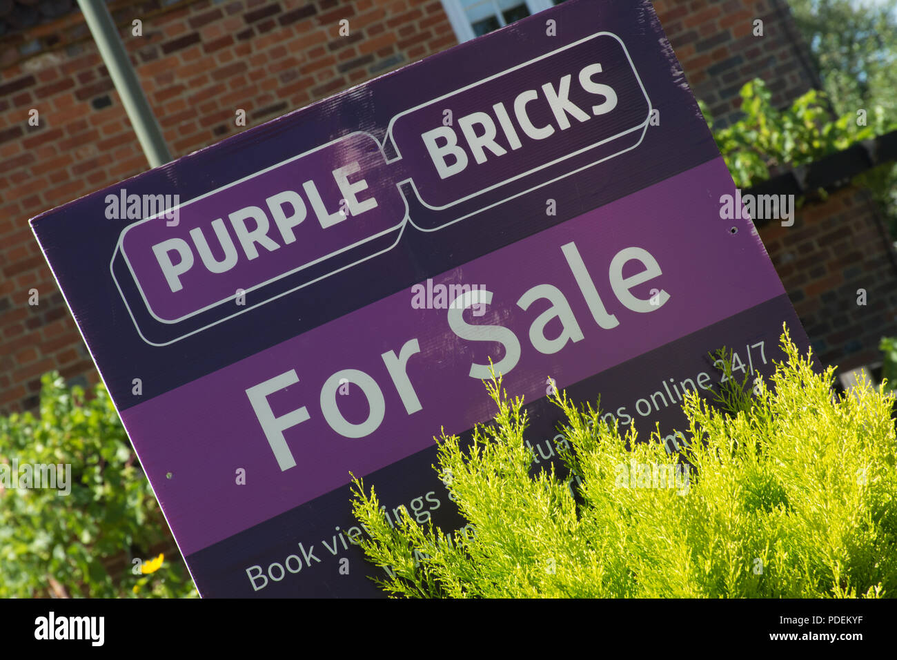 Purple bricks estate agent's for sale sign outside a house in Surrey, UK Stock Photo