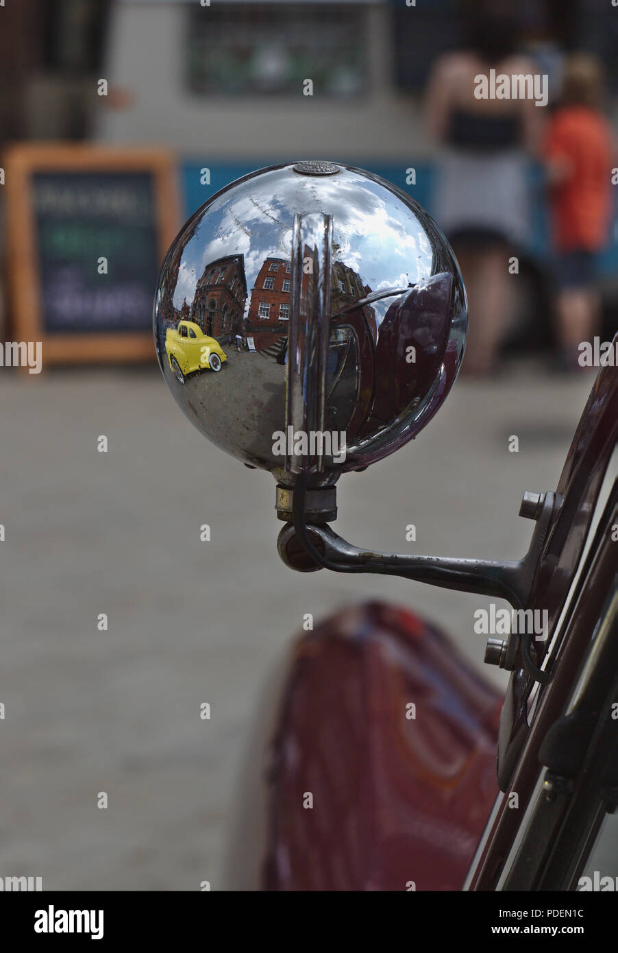 A closeup image of a classic car spotlight with the reflection of a