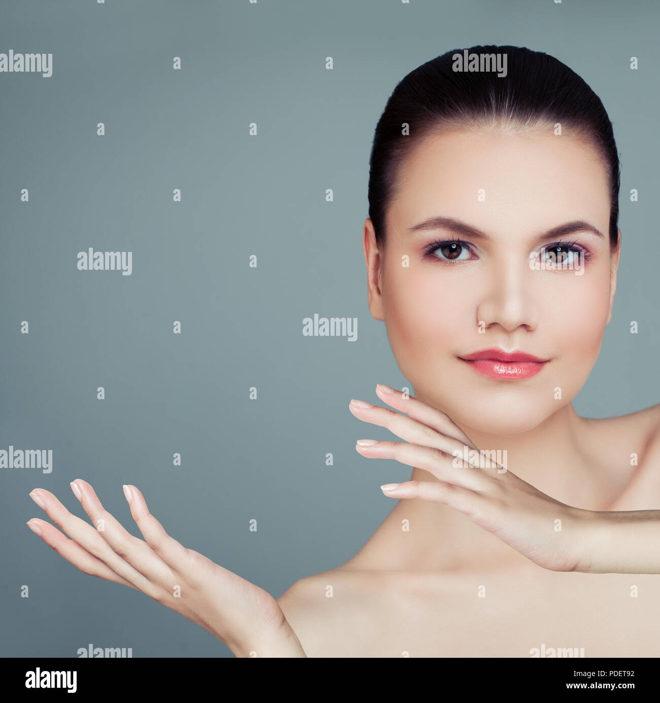 Healthy woman showing empty copy space on the open hand on blue background. Perfect female face, plastic surgery, cosmetology, skincare and wellness c Stock Photo