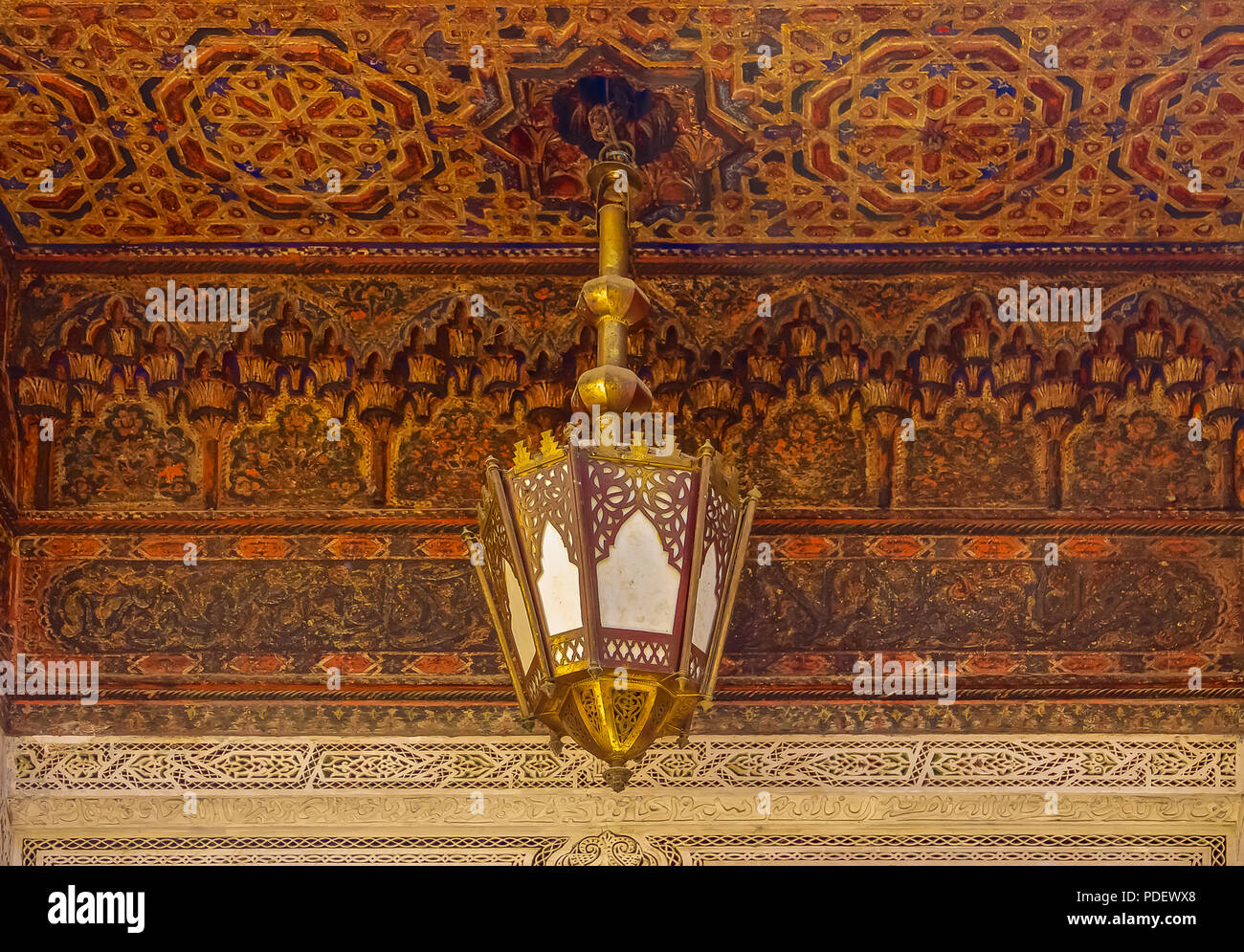 Traditional Moroccan lantern and cedar wood carved ceiling with an ornate metal filigree lamp in Fez, Morocco Stock Photo