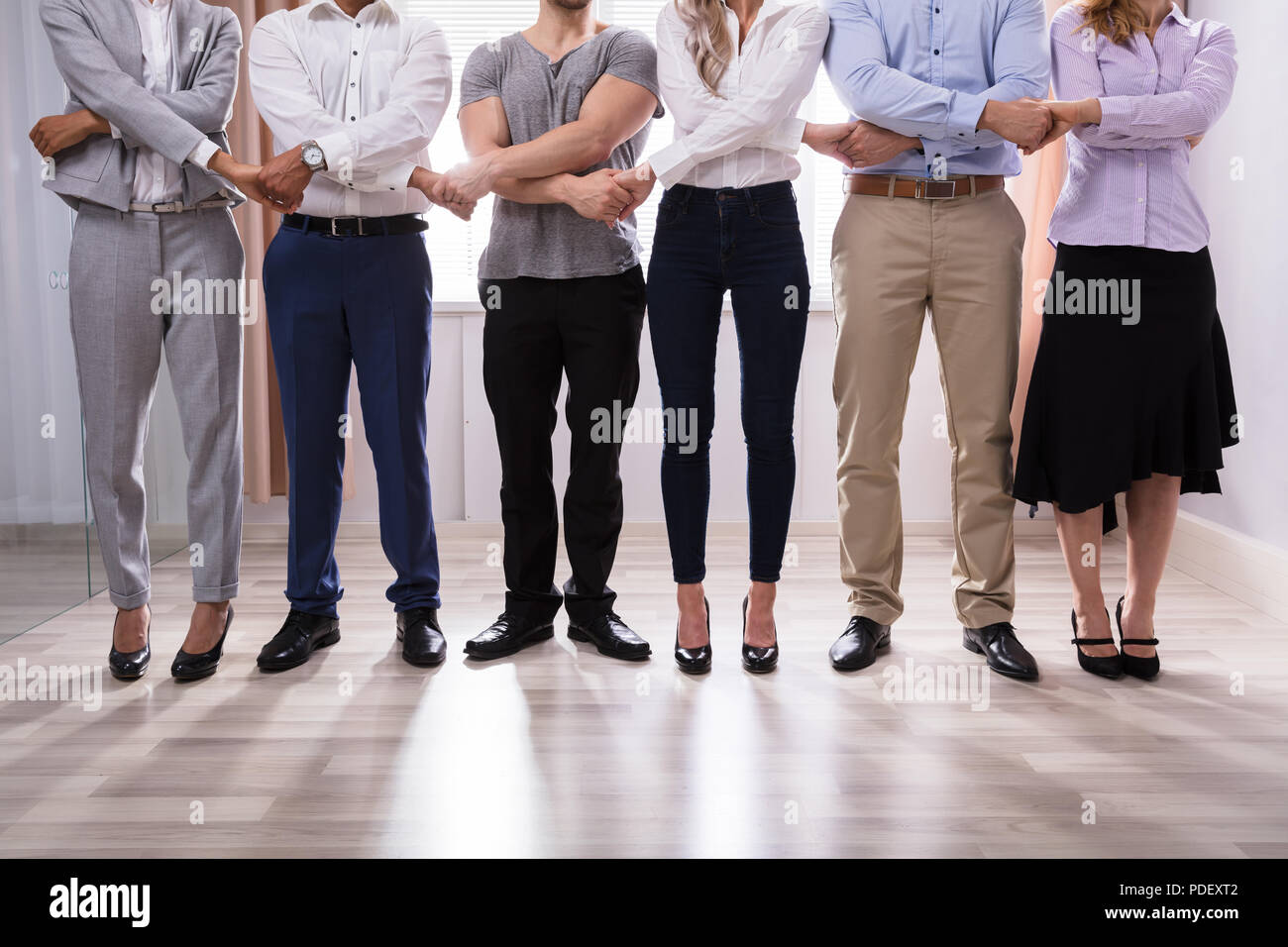 Group Of Businesspeople Standing In A Row Holding Hands Stock Photo - Alamy