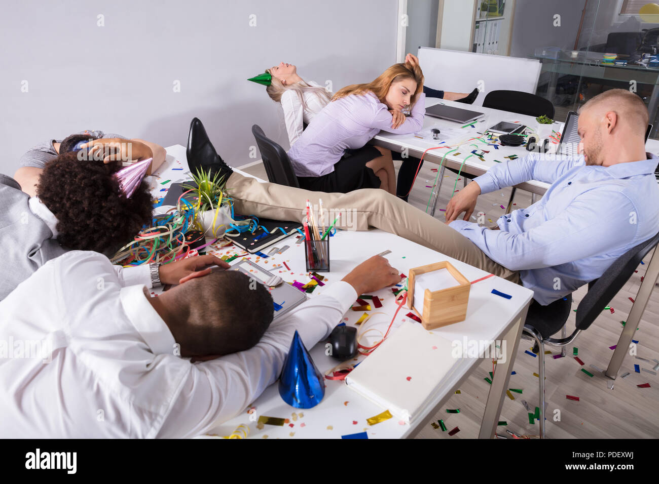 Group Of Businesspeople Sleeping In Office After New Year Party Stock