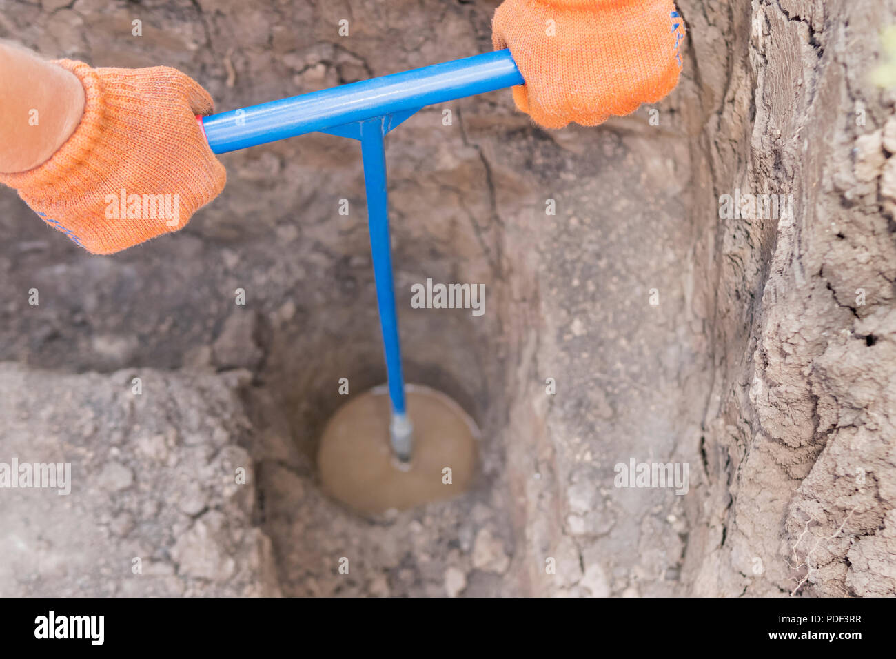 Male hands make a hole in the ground with the help of a hand drill