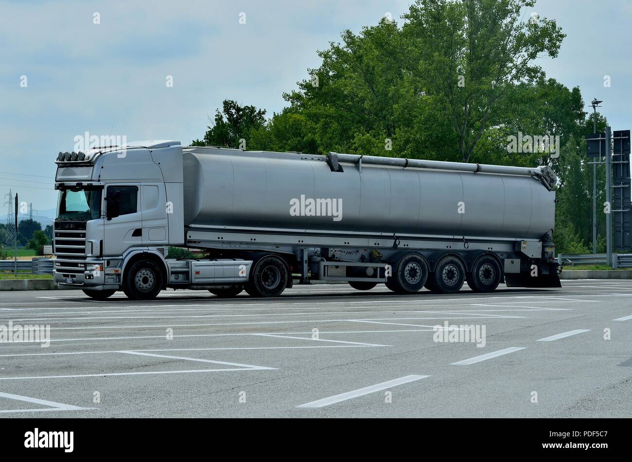 A Silver coloured Scania V580  Multi axle Trailer Truck, parked in a Truck Rest Area along side a highway near Pisa, Italy Stock Photo
