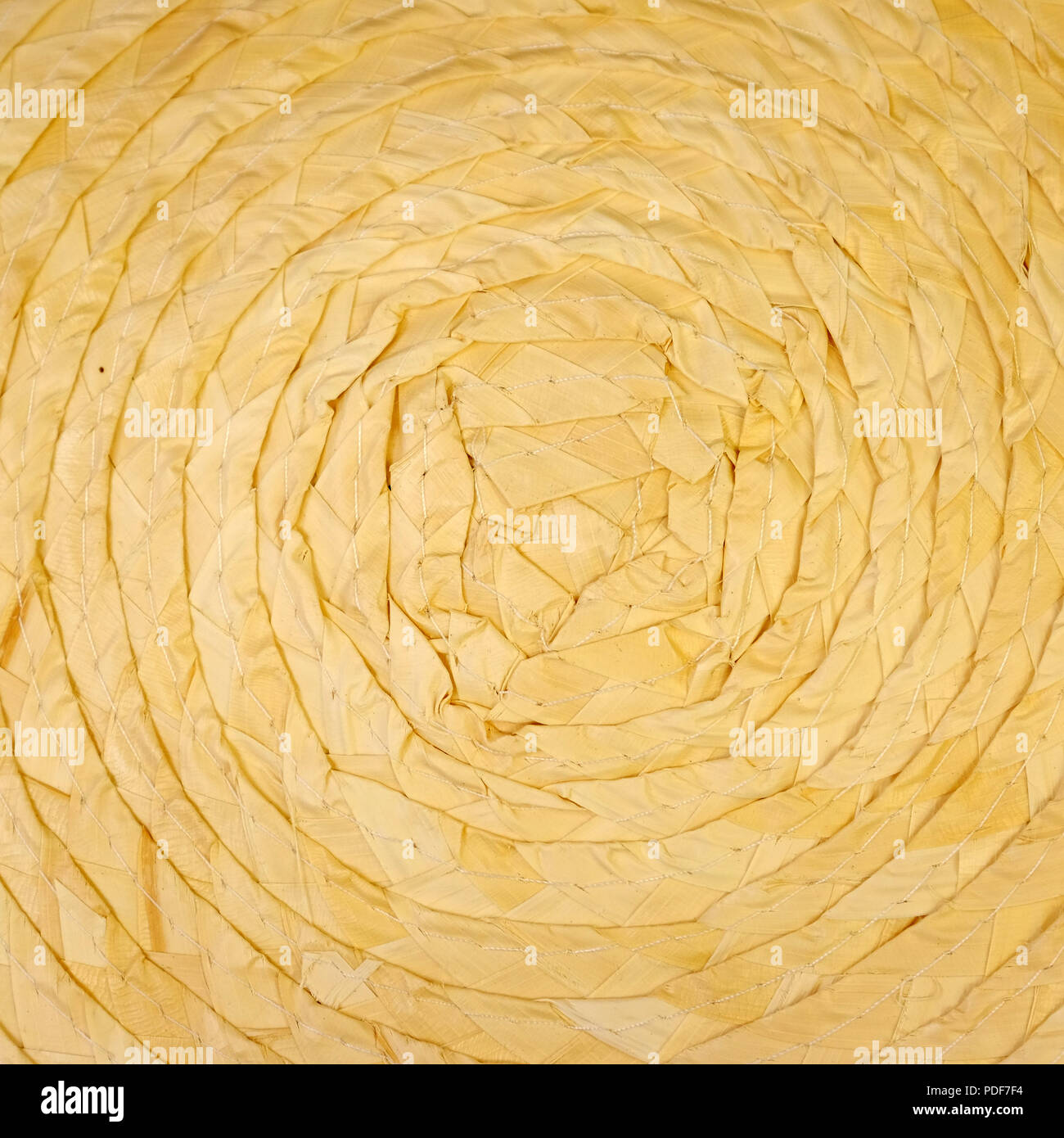 Woven circular rug made of reeds or strawyellow in color. The texture