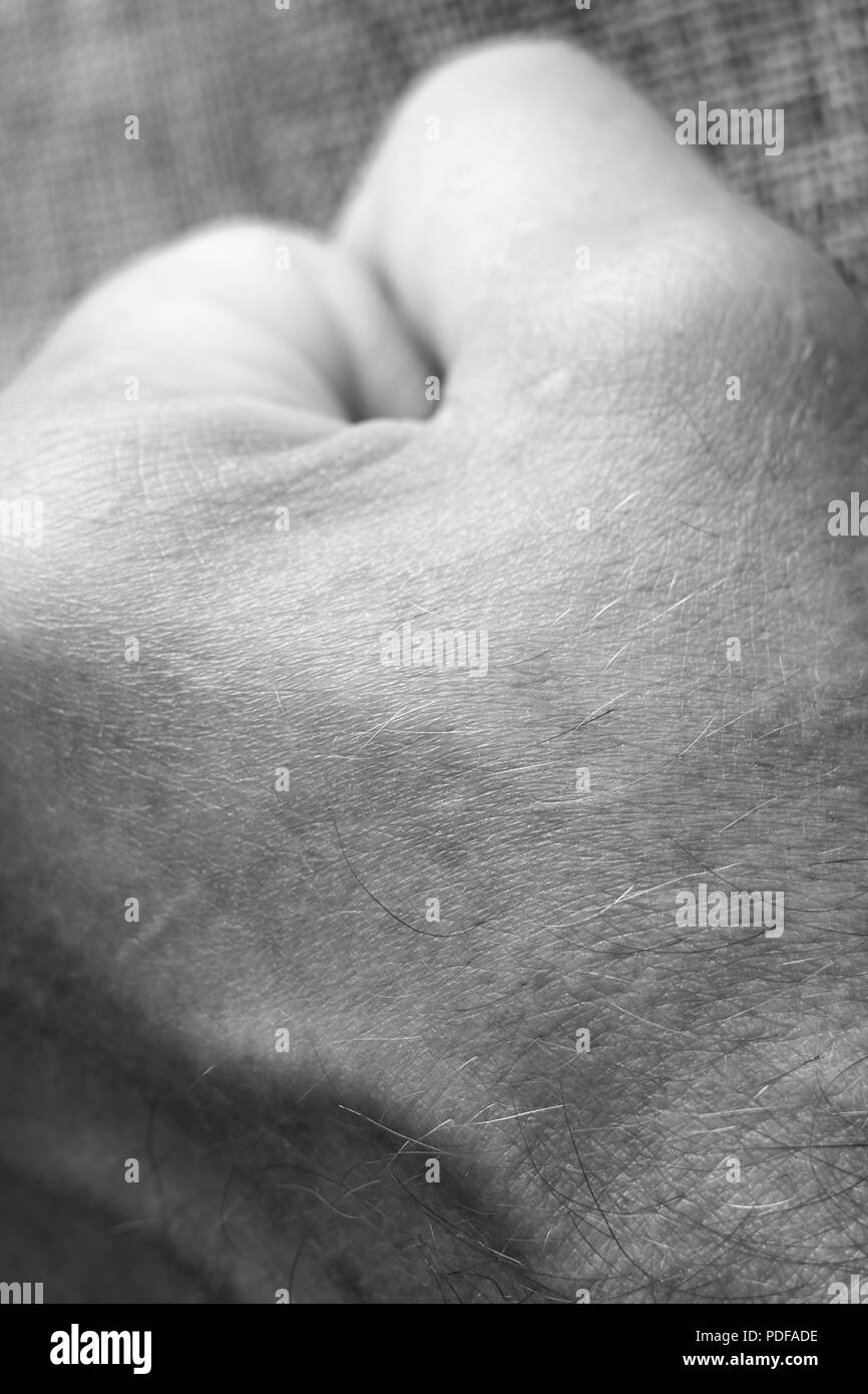 A man fists clenched on a wooden table in anger Stock Photo