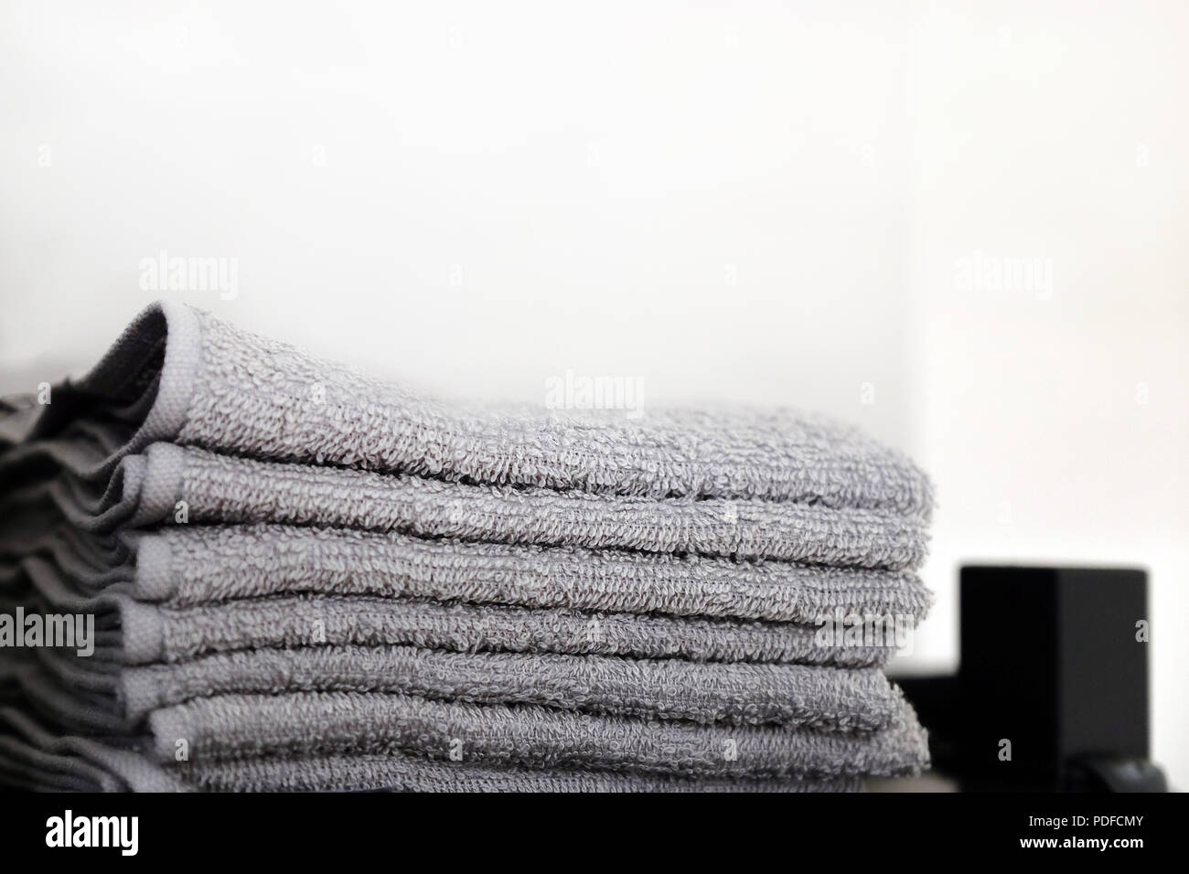 Grey and black towels are on the shelf in the bathroom. Towels hung on