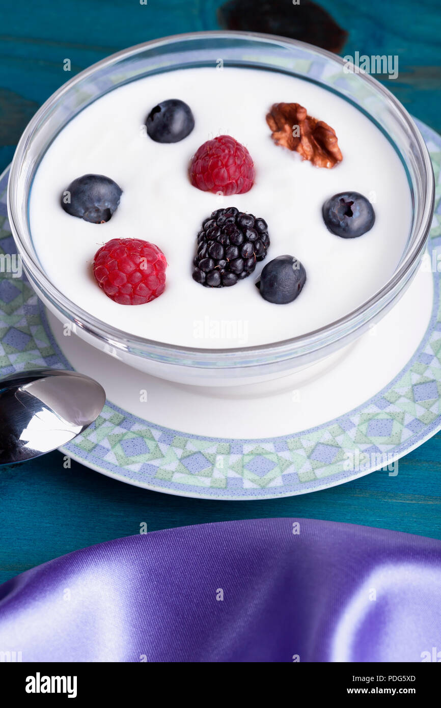 A glass bowl with yogurt and berries with nuts. Stock Photo