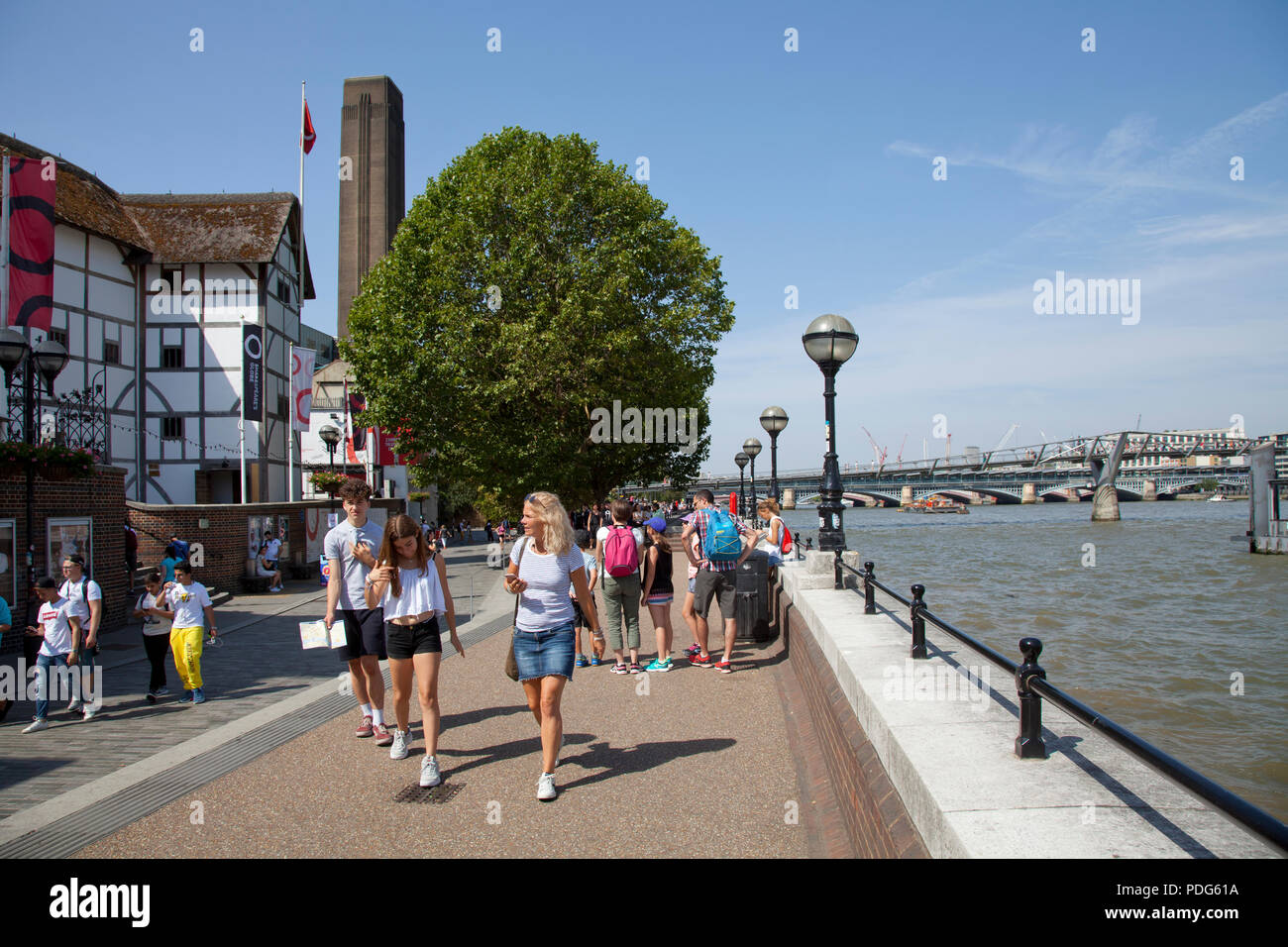 Shakespeare'sGlobe Theatre on London's Southbank with river Thames and tourists in summer Stock Photo