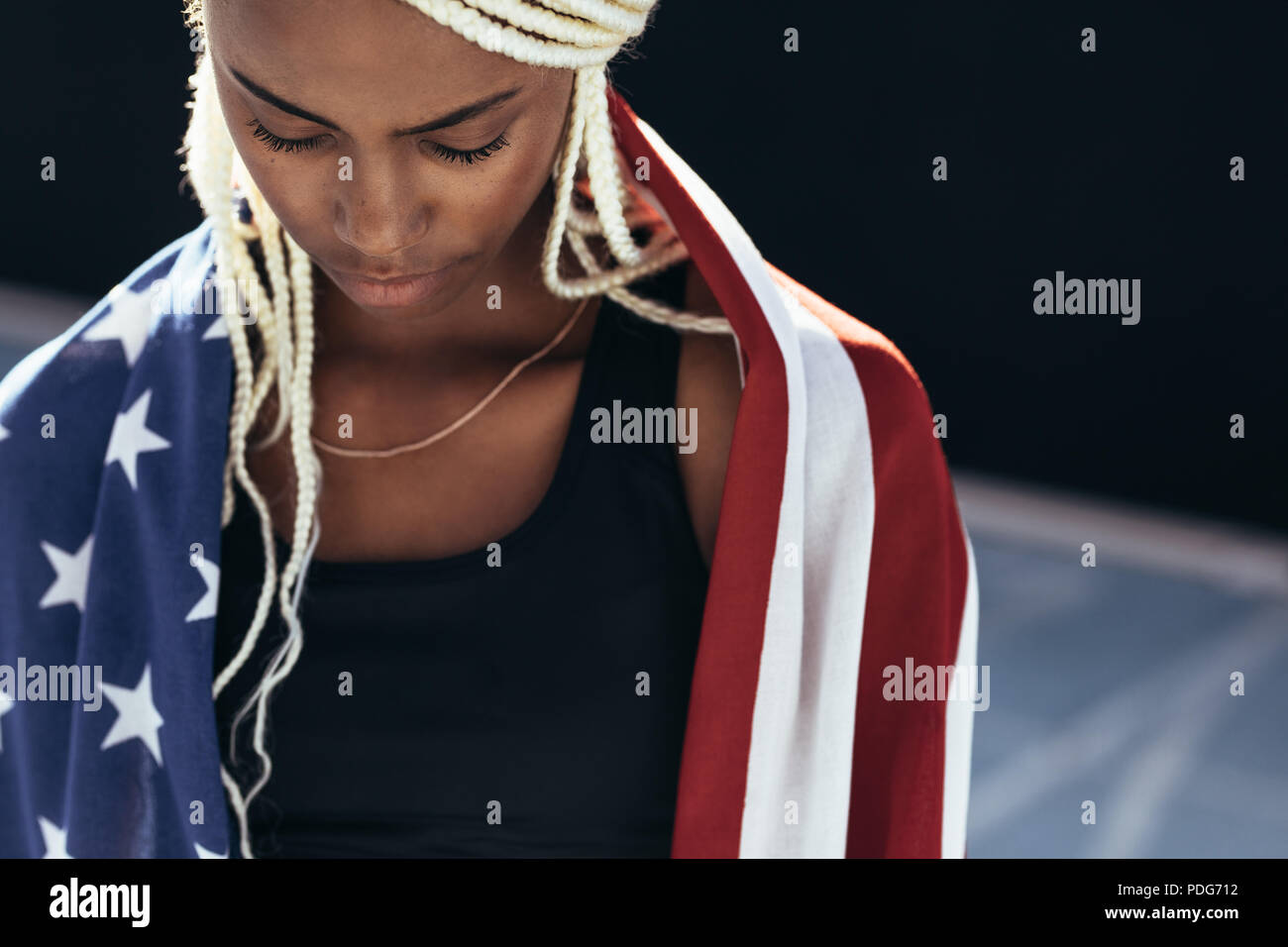 Close up of a female athlete with the american flag on her back looking down. Woman athlete with the US flag on her back after victory. Stock Photo