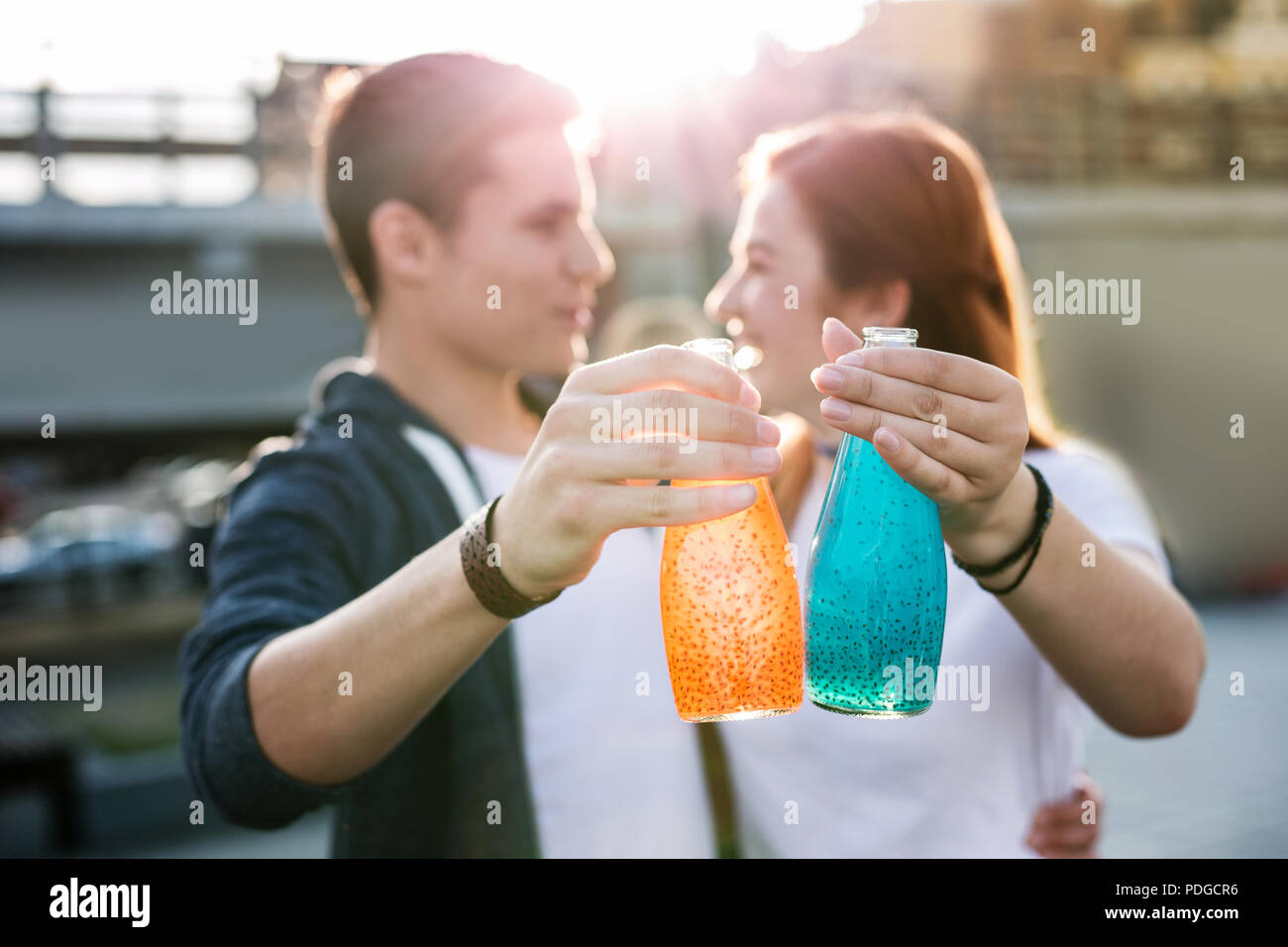 Bottles with drinks being in hands of joyful young people Stock Photo