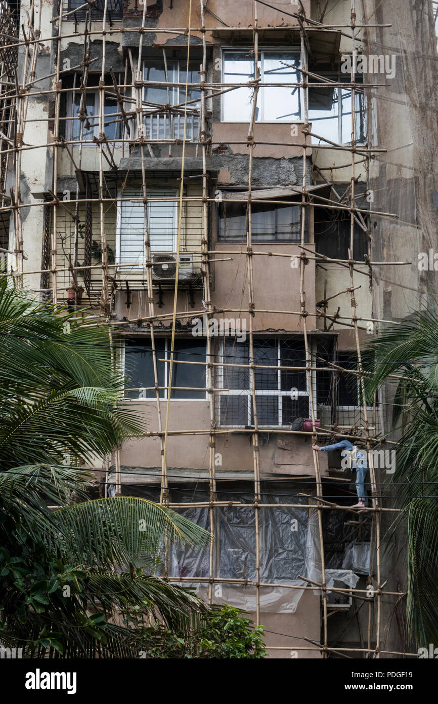 Worker on bamboo scaffolding on exterior of old apartment building in ...