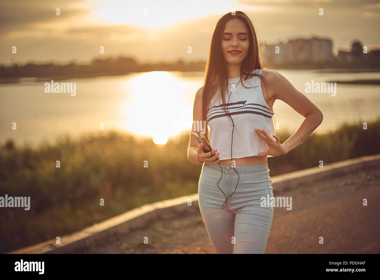 Young beautiful caucasian girl listening to music with smartphone walking in the city with headphones smiling - relax, youth, emancipation concept Stock Photo