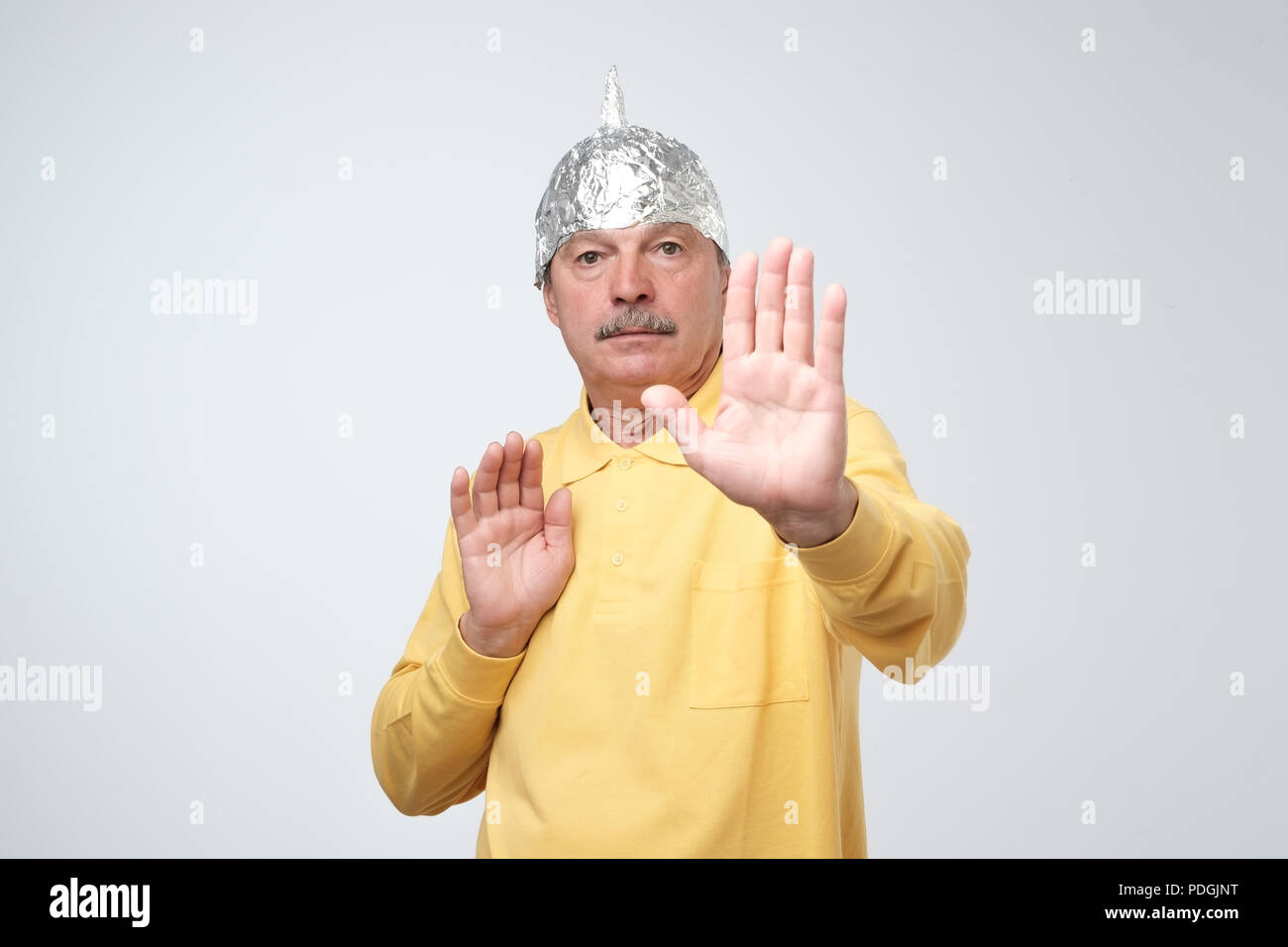 caucasian-mature-man-in-a-tin-foil-hat-displeased-hiding-from-outdoor-life-afraid-of-radiation-or-aliens-stop-sign-PDGJNT.jpg