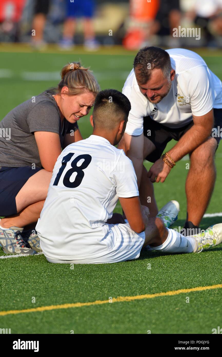 Injured player receives medical attention from a doctor and trainer while sitting upright on the turf. USA. Stock Photo