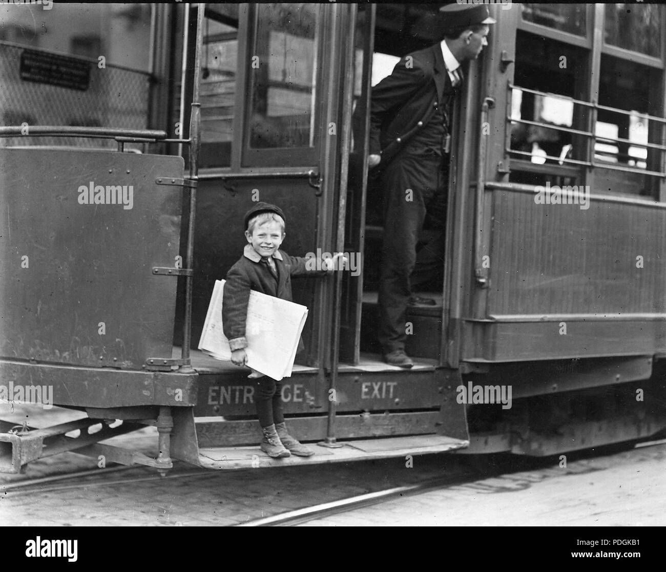 Five year old Newsie jumps on and off streetcars to sell newspapers 1910 Stock Photo