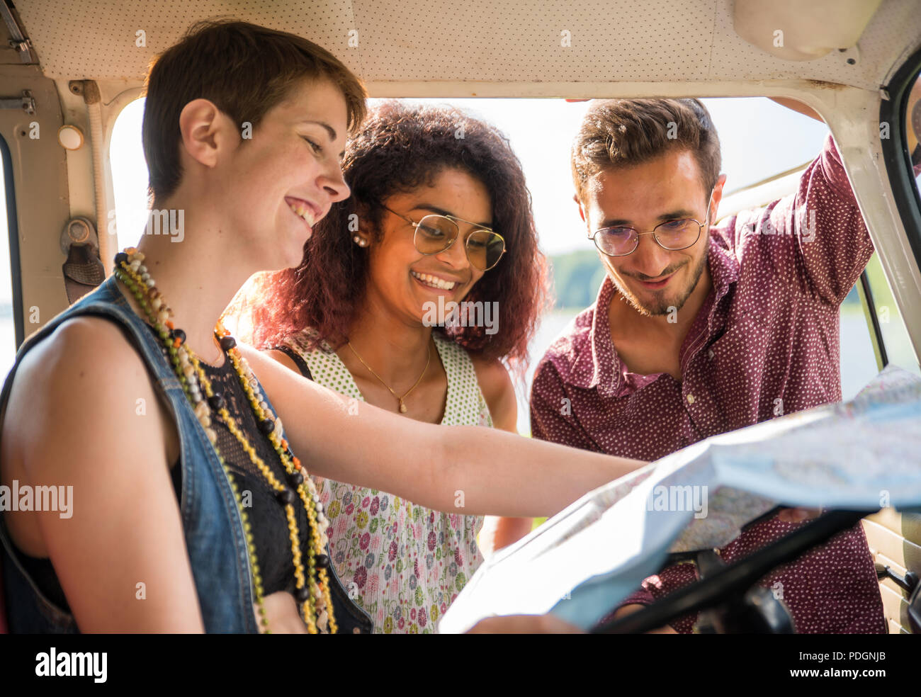 Mixed group of happy young people in a car looking at a map Stock Photo