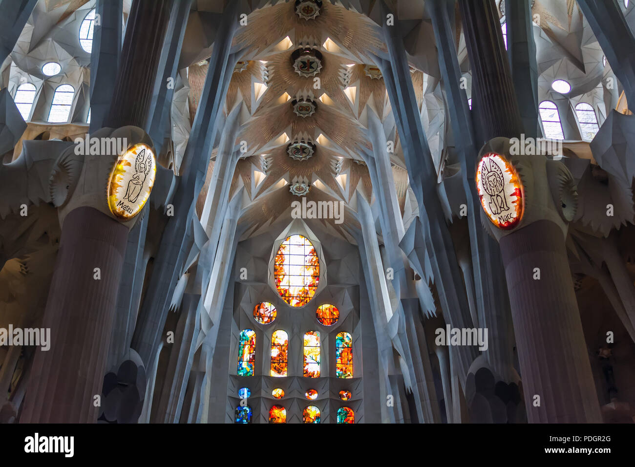Architectural details of colorful stained glass window, ceiling and lights on columns inside Sagrada Familia - large unfinished Roman Catholic church  Stock Photo