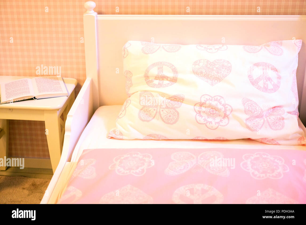 Children's room with pink walls, wooden floor, bed with pink pillow and