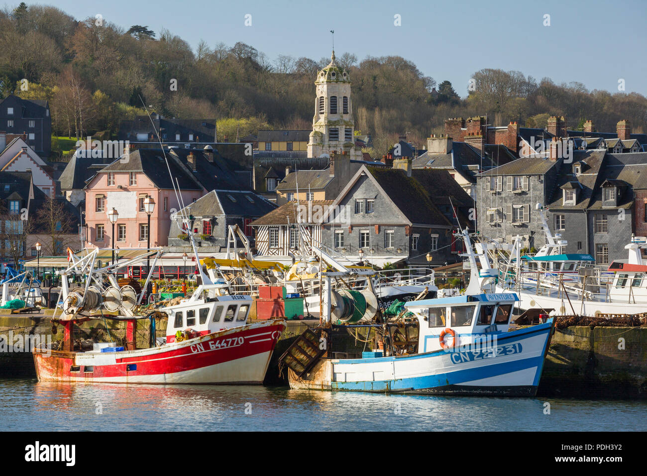 Two colourful fishing boats moored on the quayside with the St. Leonard's Church behind, Honfleur, Normandy, France Stock Photo