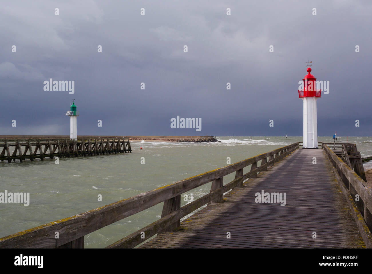 The green and red painted West and East lighthouses protecting each side of the harbour entrance at Trouville-sur-Mer, Normandy, France with a storm c Stock Photo