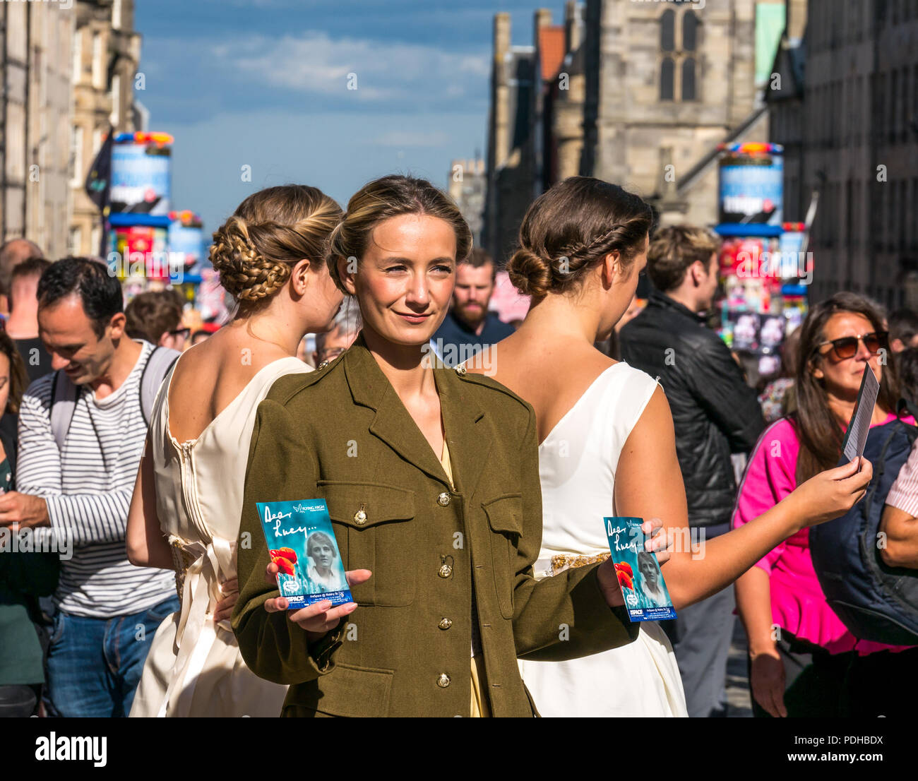 Edinburgh, Scotland, UK. 9th August 2018. Edinburgh Fringe Festival, Royal Mile, Edinburgh, Scotland, United Kingdom. On a sunny festival day the Virgin Money sponsored street festival is packed with people and fringe performers. A group of pretty young women dressed in World War II era costumes hand out flyers for their Fringe Show called Dear Lucy Stock Photo